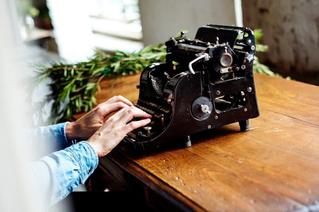 Young woman typing on old typewriter