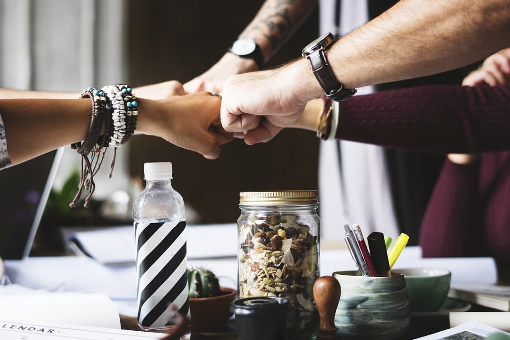 Get more done without growing your team Team hands in a group over table