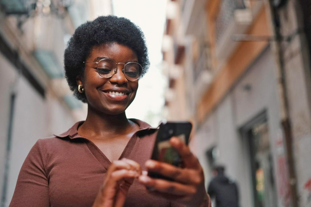 Africa’s diaspora is flocking to fintech services African woman holding a phone in her hand and smiling